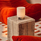 Cordless table lamp Dou Small, Calacatta Viola marble, styled on a travertine side table beside a red sofa