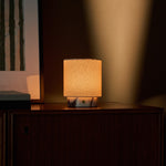Dou Small rechargeable table lamp in white marble glowing on a dark wood sideboard at dusk