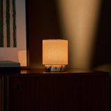 Dou Small rechargeable table lamp in white marble glowing on a dark wood sideboard at dusk