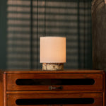 Oplaadbare tafellamp Dou Small in geel Calacatta Vionaro marmer op een houten dressoir in de avondschemering