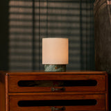 Cordless table lamp Dou Small in Ice Green marble casting warm light through striped blind shadows