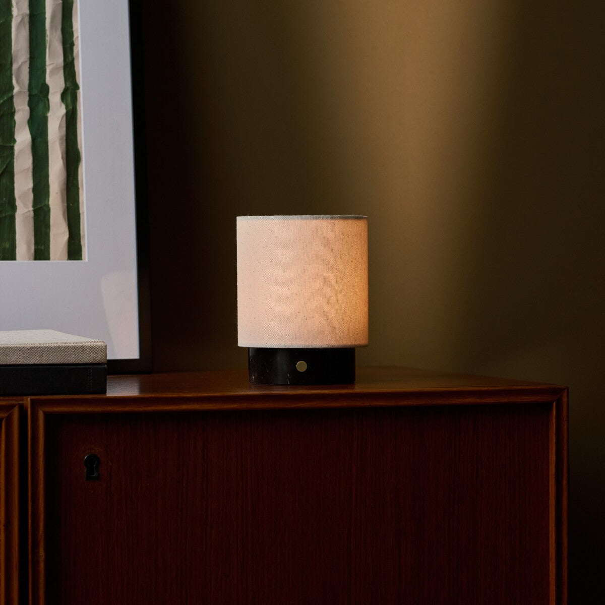 Cordless table lamp Dou Small on a walnut cabinet in Nero Marquina black marble beside a framed botanical print
