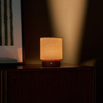 Dou Small cordless table lamp in red travertine on a wood cabinet with striped artwork close-up
