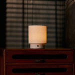 Dou Small rechargeable table lamp in Rosa Aurora marble on a vintage dresser with blind-shadow light