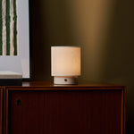 Dou Small cordless table lamp in Rosa Aurora marble beside striped wall art on a walnut sideboard