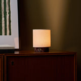 Tavellio Dou Small cordless table lamp in Rosso Levanto marble casting warm light on a wooden cabinet