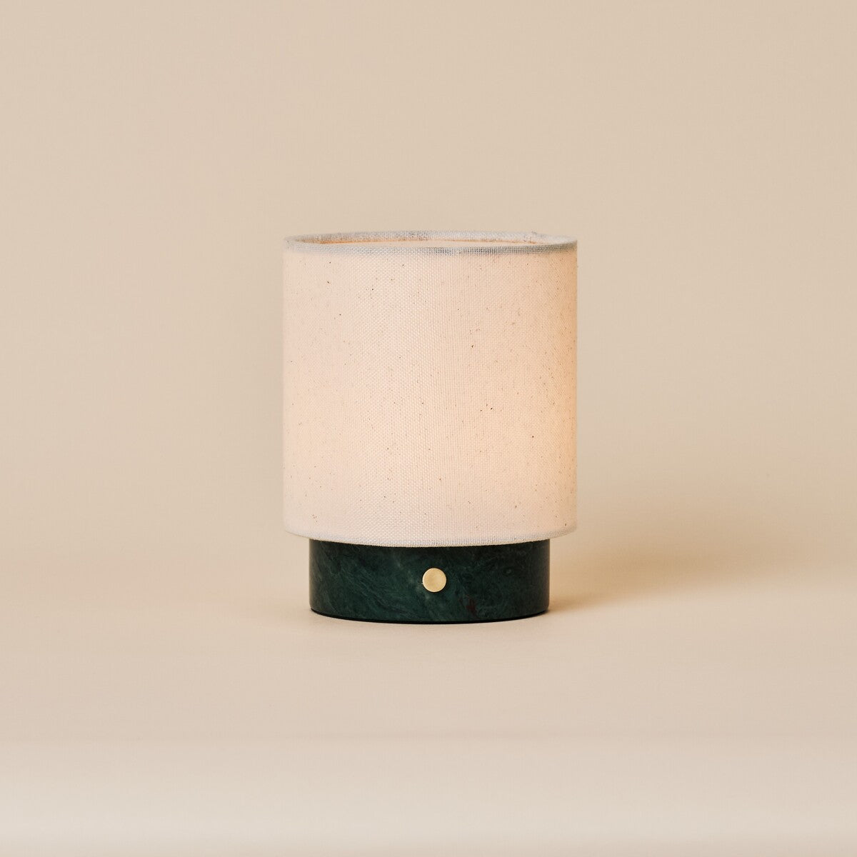 Rechargeable table lamp Dou Small in Verde Alpi green marble with a natural linen shade on a beige backdrop