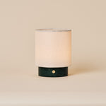 Rechargeable table lamp Dou Small in Verde Alpi green marble with a natural linen shade on a beige backdrop