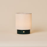 Rechargeable table lamp Dou Small in Verde Alpi green marble with a natural linen shade on a beige backdrop
