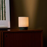 Tavellio Dou Small cordless table lamp in Verde Alpi green marble glowing on a wooden cabinet