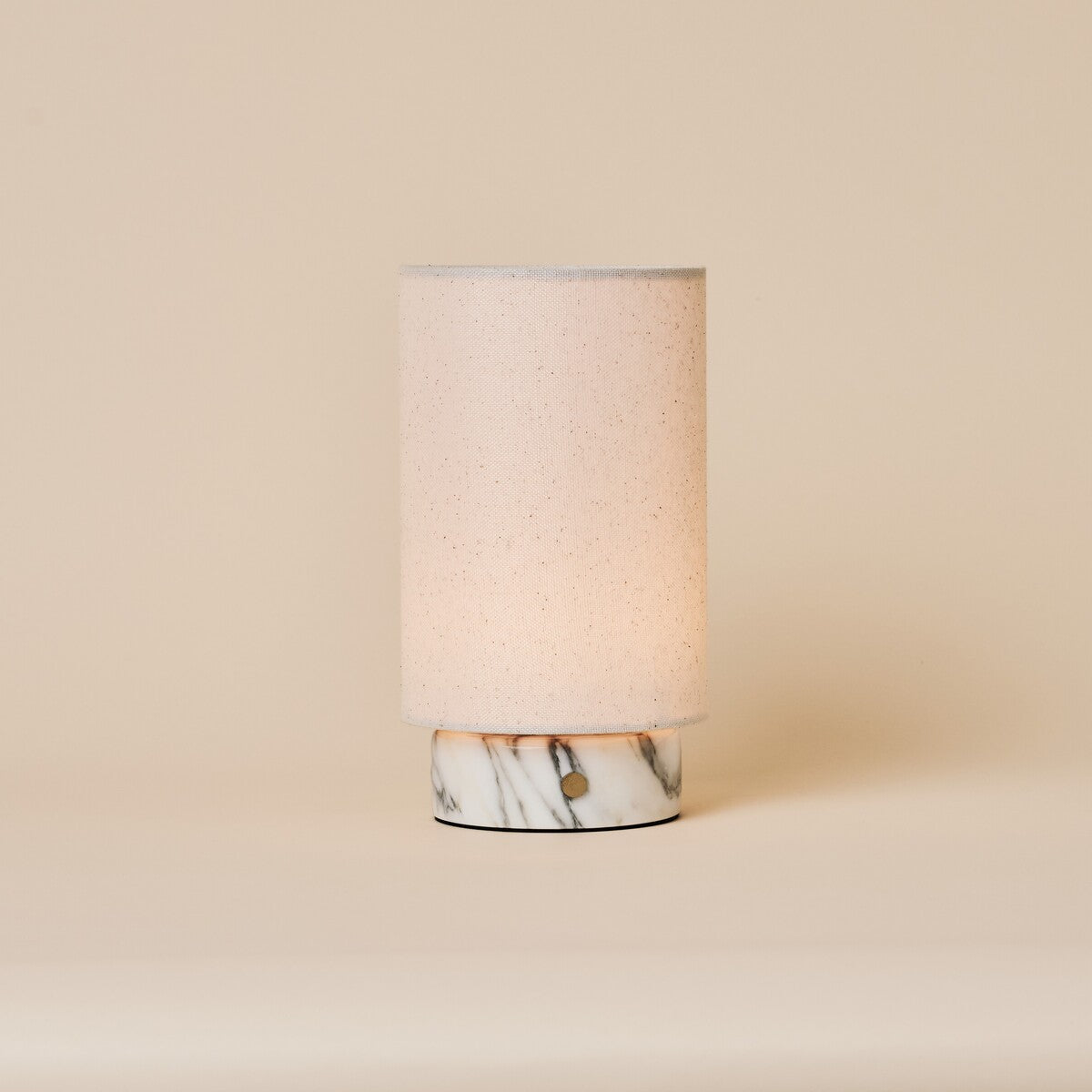 Lampe de table Floris marbre Arabescato sans fil Tavellio - photo studio sur fond creme - abat-jour cylindrique en lin allume