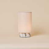 Lampe de table Floris marbre Arabescato sans fil Tavellio - photo studio sur fond creme - abat-jour cylindrique en lin allume