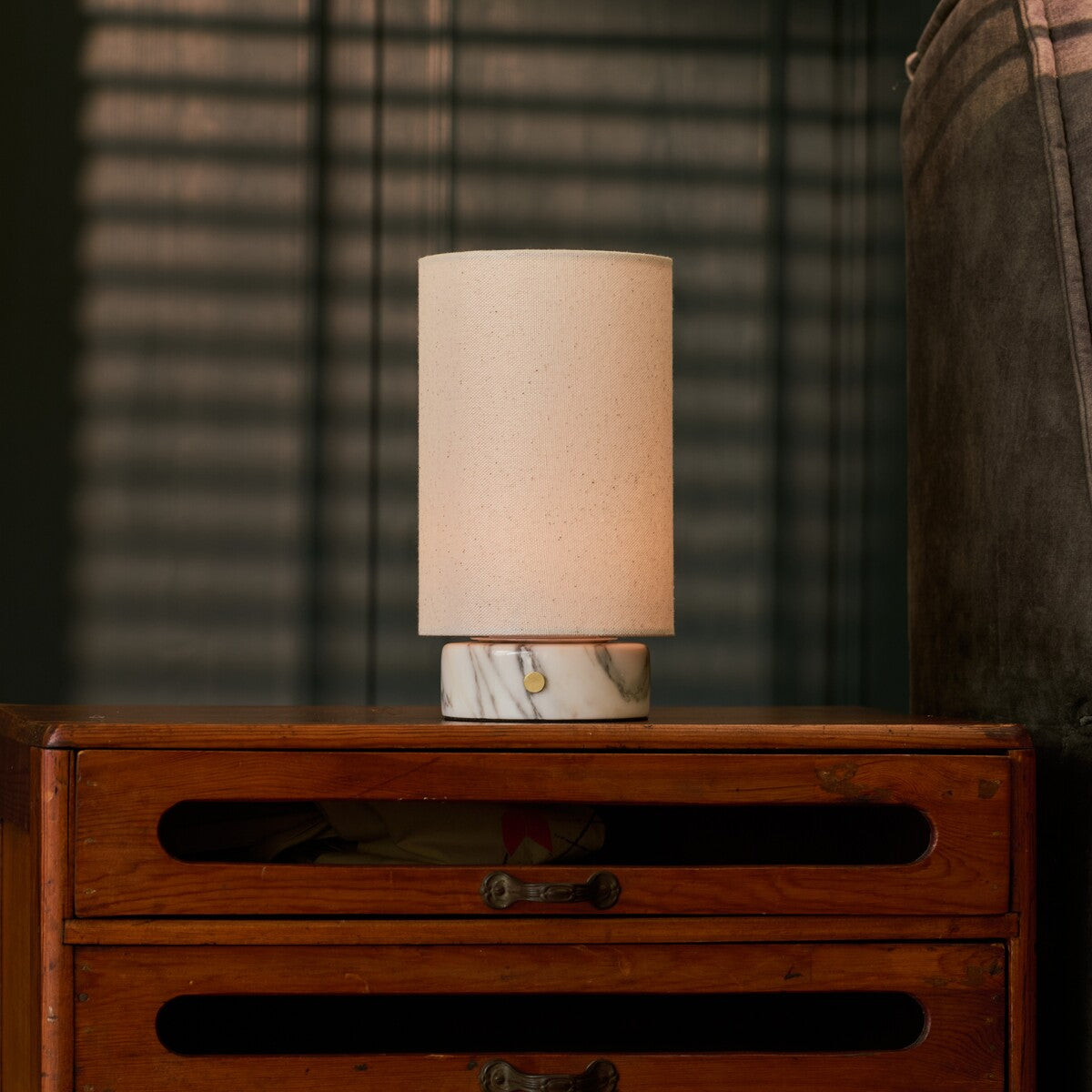 Lampe de table Floris marbre Arabescato rechargeable Tavellio - posee sur une commode rustique en bois - ambiance chaleureuse du soir