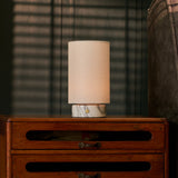 Lampe de table Floris marbre Arabescato rechargeable Tavellio - posee sur une commode rustique en bois - ambiance chaleureuse du soir