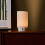 Lampe de table Floris marbre Arabescato rechargeable Tavellio - posee sur un meuble en bois - lumiere chaude pres d'un cadre encadre