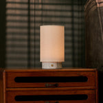 Floris rechargeable table lamp with white marble base on a vintage wood dresser in a dim bedroom setting