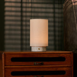 Floris rechargeable table lamp with white marble base on a vintage wood dresser in a dim bedroom setting