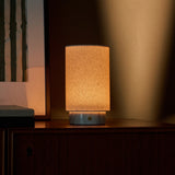 Tavellio Floris cordless table lamp on a bedroom dresser, warm glow against striped window blinds