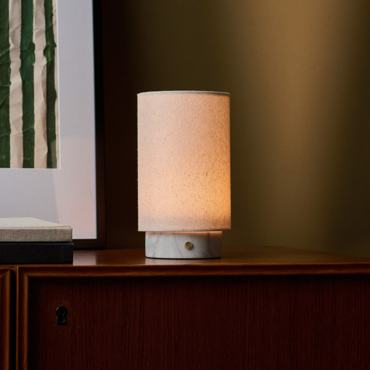 Floris rechargeable table lamp with white marble base on a wood sideboard, framed art and olive wall behind
