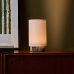 Tavellio Floris cordless table lamp in Calacatta Viola marble glowing on a sideboard against a warm lit wall