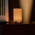 Floris rechargeable table lamp in Calacatta Viola marble lit on a wooden sideboard beside a framed art print