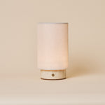Floris cordless table lamp with beige travertine marble base on a cream studio backdrop