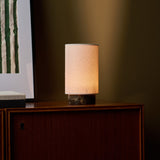 Lampe de table Floris marbre Emperador Dark sans fil Tavellio - allumee sur un meuble en bois pres du cadre a rayures vertes