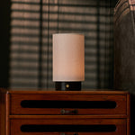 Cordless table lamp with black Nero Marquina marble base glowing on a wooden dresser at dusk