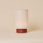 Floris cordless table lamp in red travertine, brass touch dimmer visible on the stone base, studio shot