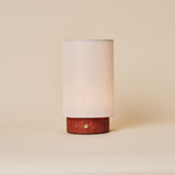 Floris cordless table lamp in red travertine, brass touch dimmer visible on the stone base, studio shot