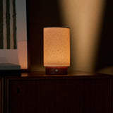Tavellio Floris red travertine cordless table lamp glowing on a sideboard beside framed wall art at dusk