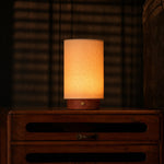 Tavellio Floris rechargeable table lamp with red travertine base glowing on a wood dresser in a dim bedroom