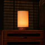 Tavellio Floris rechargeable table lamp with red travertine base glowing on a wood dresser in a dim bedroom