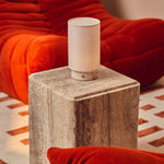 Tavellio Floris Rosa Aurora marble rechargeable table lamp on a travertine side table beside a bold orange sofa