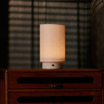 Tavellio Floris Rosa Aurora marble rechargeable table lamp glowing softly with blind-slat shadows in a bedroom