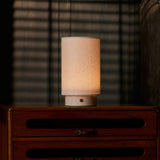 Tavellio Floris Rosa Aurora marble rechargeable table lamp glowing softly with blind-slat shadows in a bedroom