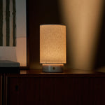 Floris cordless table lamp with Rosa Aurora marble base glowing on a wood sideboard at night