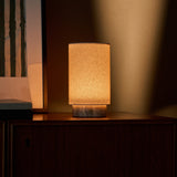 Floris Silver Travertine lampe de table sans fil Tavellio – sur un buffet en bois, ambiance tamisée avec un cadre au mur en arrière-plan