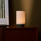 Cordless table lamp Floris Verde Alpi Marble glowing on a walnut cabinet beside framed art