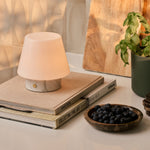Tafellamp oplaadbaar Hooch Small Bianco Statuarietto Marble op boeken naast een kom bosbessen en basilicum