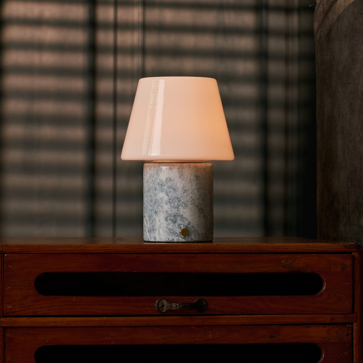 Tafellamp oplaadbaar Hooch in Blue Calcite marmer op een nachtkastje in een schaars verlichte slaapkamer