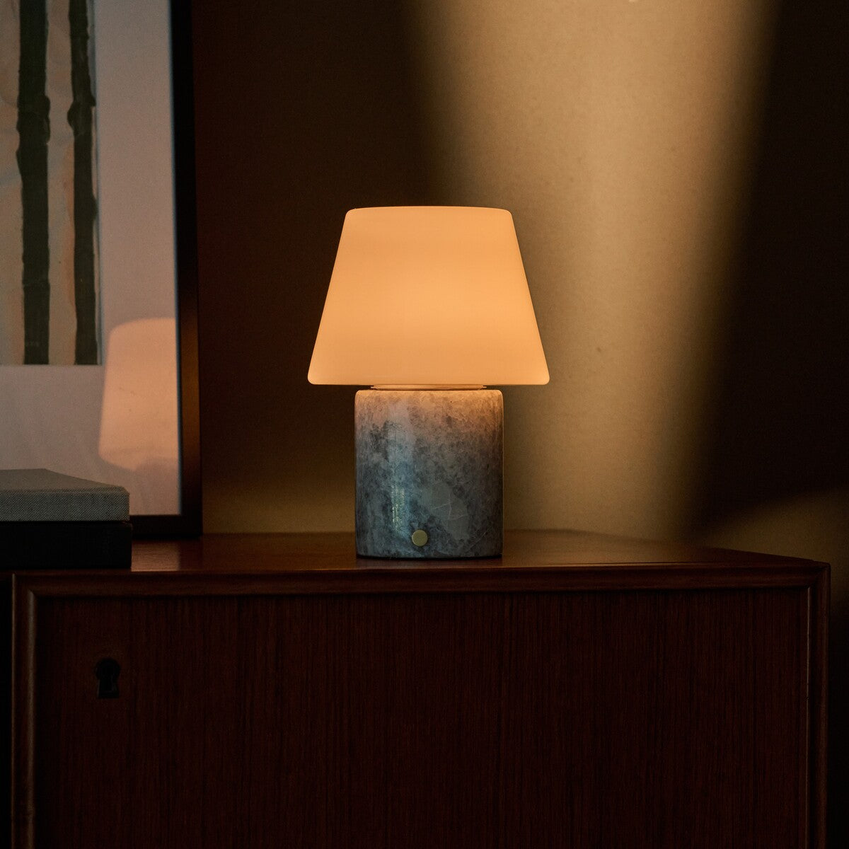 Oplaadbare tafellamp Hooch in Blue Calcite marmer op een houten kastrand in schemerlicht