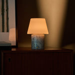 Oplaadbare tafellamp Hooch in Blue Calcite marmer op een houten kastrand in schemerlicht