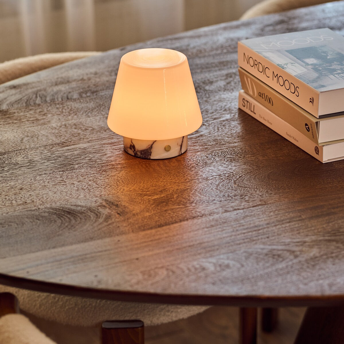 Tafellamp oplaadbaar Hooch Small in Calacatta Vionaro wit marmer op een houten salontafel bij boeken