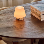 Tafellamp oplaadbaar Hooch Small in Calacatta Vionaro wit marmer op een houten salontafel bij boeken