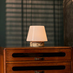 Tafellamp oplaadbaar Hooch Small in geel marmer, brandend op een vintage houten dressoir in de avond