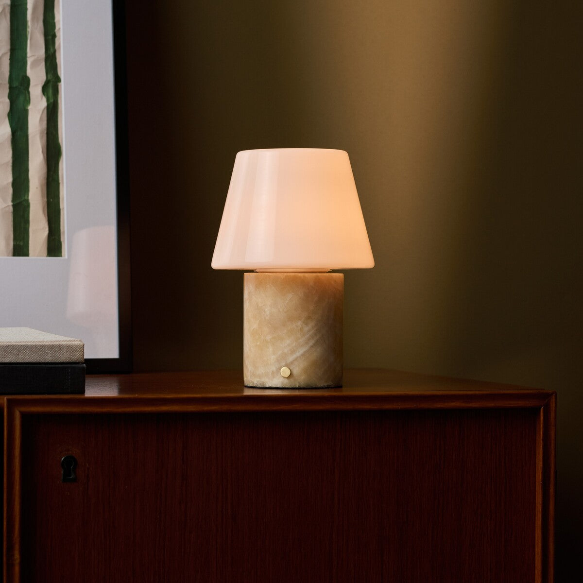 Tafellamp oplaadbaar Hooch in Honey Onyx marmer met warm licht op een donker houten dressoir