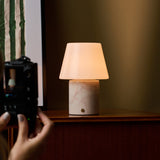 Oplaadbare tafellamp Hooch in Rosa Aurora marmer tijdens een fotoshoot op een houten dressoir
