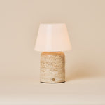 Oplaadbare tafellamp Hooch Large in beige travertin met taps toelopende opaalglazen kap op een effen achtergrond