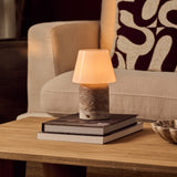 Tafellamp oplaadbaar Hooch Large in silver travertine op een stapel boeken naast een beige fauteuil